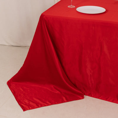 Red tablecloth draped elegantly on a table with a white plate.