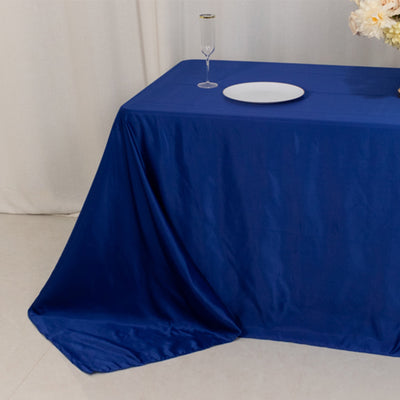 Blue tablecloth draped over a table with a plate and glass on top.