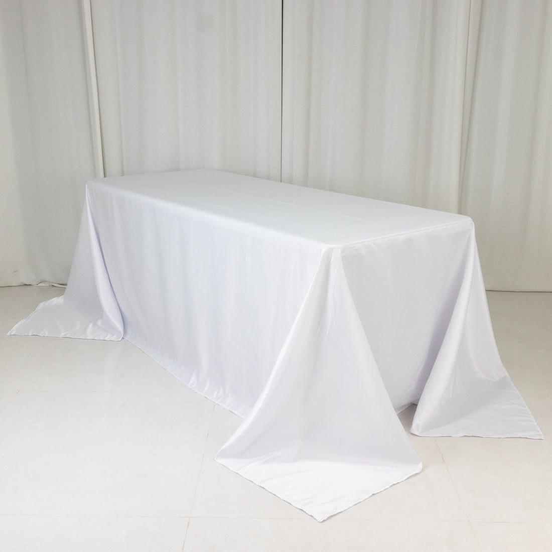White table covered with a smooth tablecloth in a studio setting.