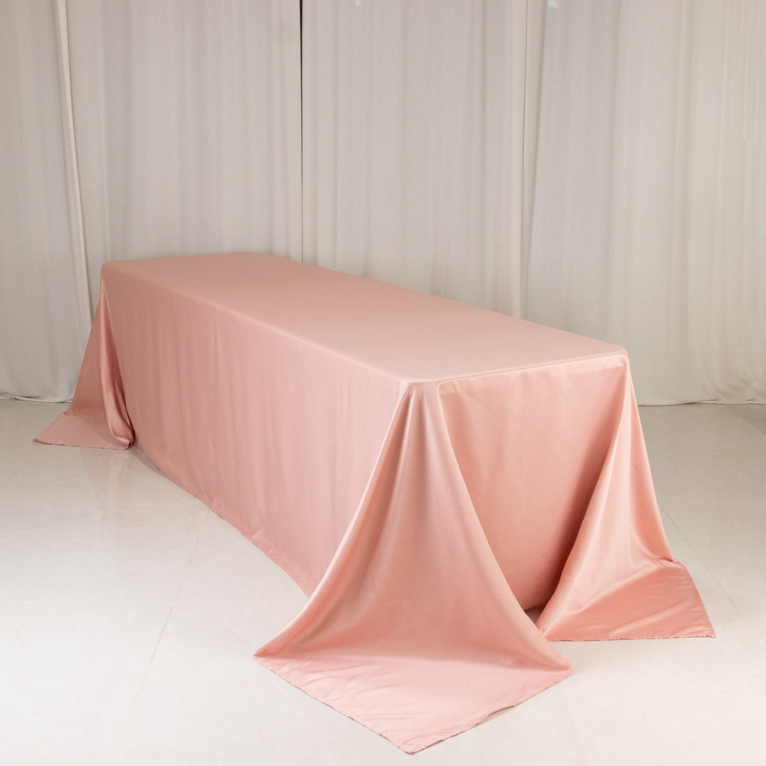 Pink tablecloth draped over a long table in a studio setting.