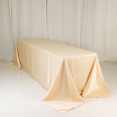 Beige satin tablecloth draped over a table in a studio setting.