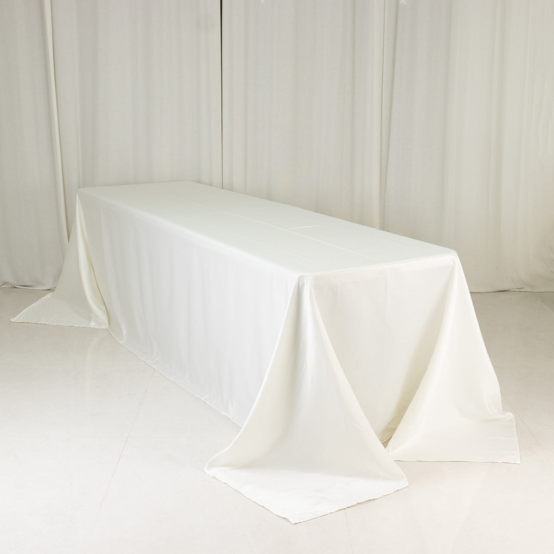 White table with draped tablecloth in a studio setting