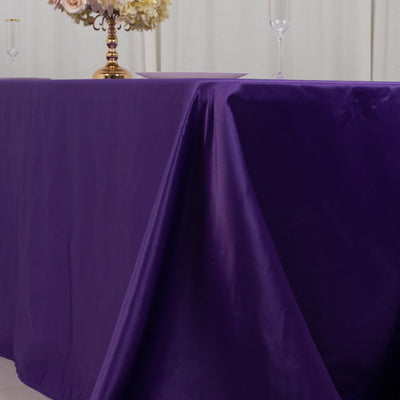 Purple tablecloth draped over a table with floral centerpiece