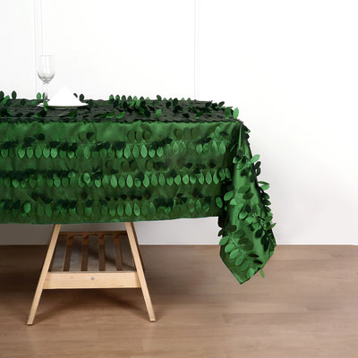 Green leaf tablecloth draped over a wooden table with glassware.