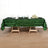 Green sequin tablecloth on a wooden table with glassware and floral accents.