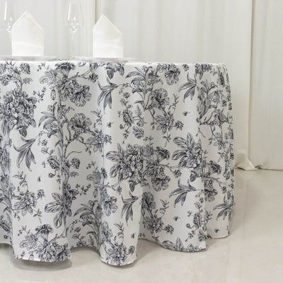 Floral tablecloth with intricate black and white design on a dining table.