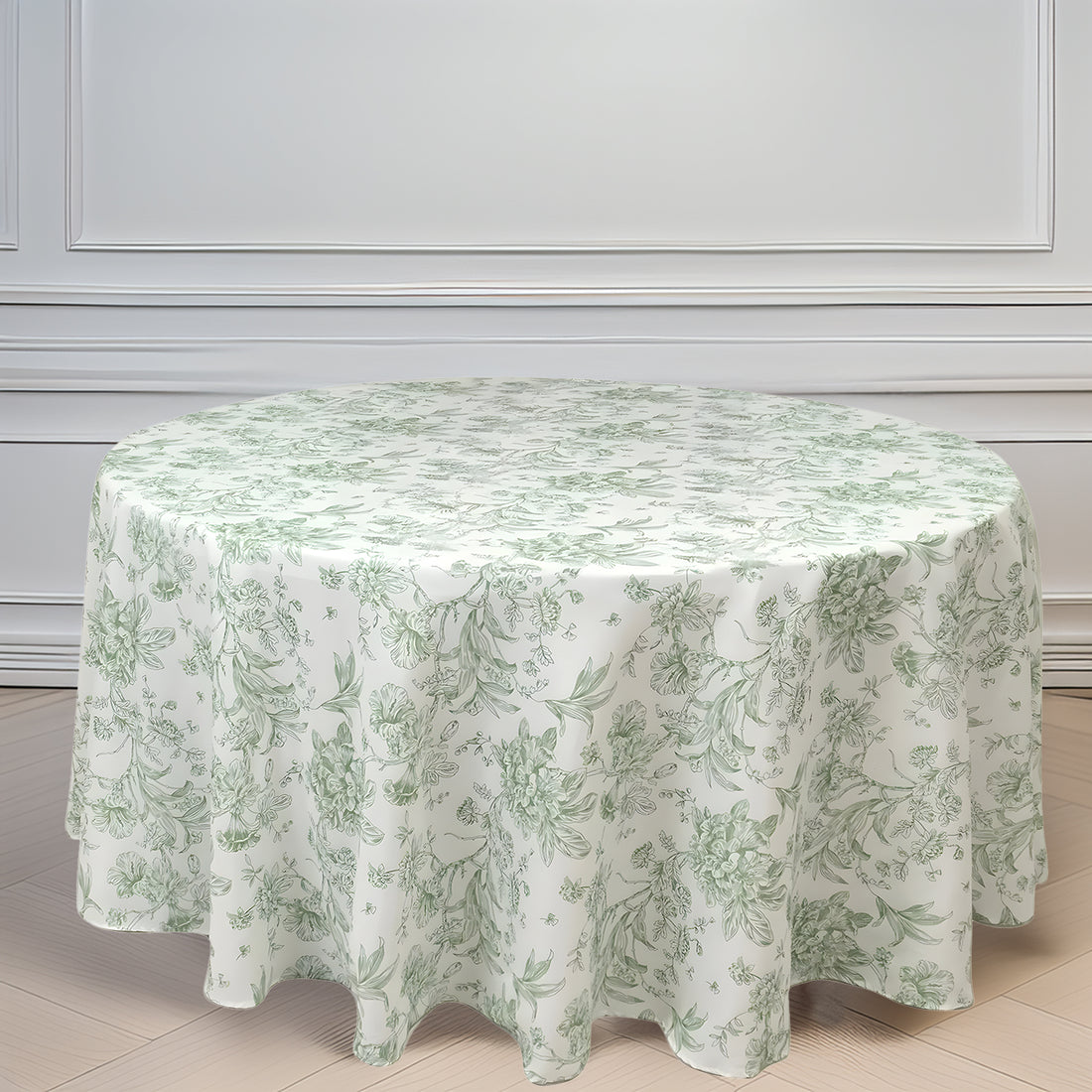 Round floral tablecloth in soft green and white design on a light wood floor.