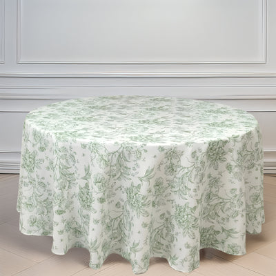 Round floral tablecloth in soft green and white design on a light wood floor.