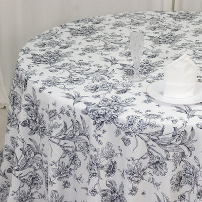 Floral-patterned tablecloth on a round table with glassware and napkin.