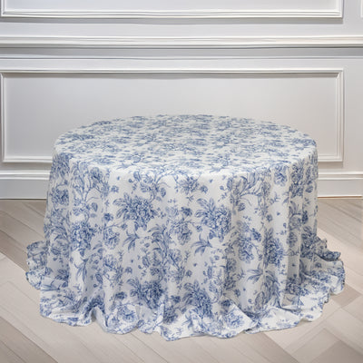 Floral patterned round tablecloth on a wooden floor.