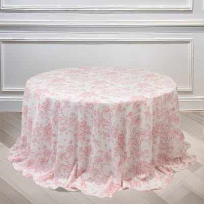 Round floral tablecloth in soft pink and white tones on a plain backdrop.