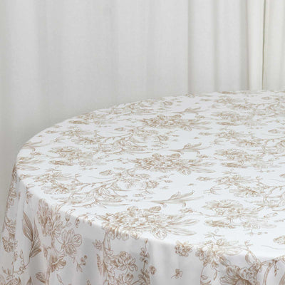 White floral tablecloth on round table against a neutral curtain backdrop