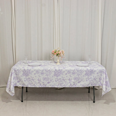 Floral tablecloth on a dining table with a vase of flowers and glassware.