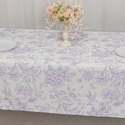 Floral patterned tablecloth draped on a table with a vase of flowers.