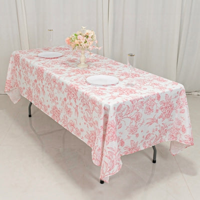 Floral-patterned tablecloth draped over a table with plates and flowers.