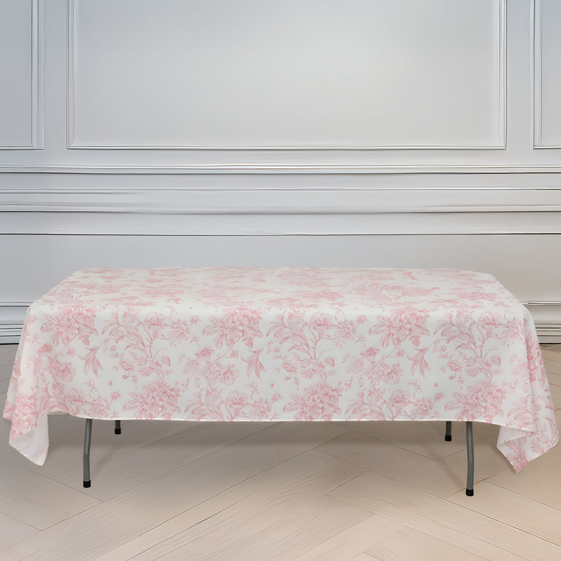 Pink floral tablecloth draped over a folding table in a bright room.