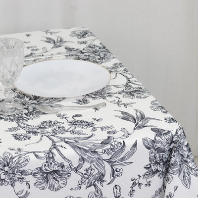 Floral patterned tablecloth with elegant glassware and plate on a dining table.