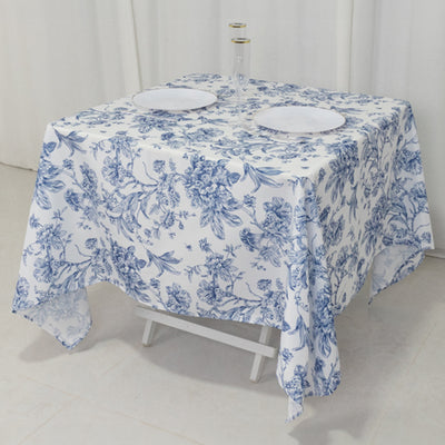 Floral blue and white tablecloth on a table with plates and glasses.