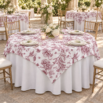 Elegant round table with floral tablecloth and gold chairs at a wedding reception