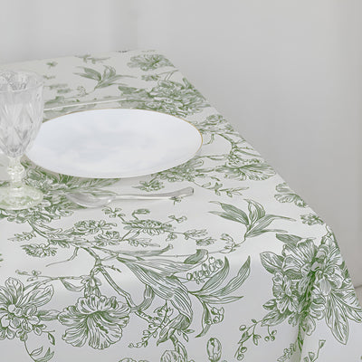 Floral patterned tablecloth with glassware and plate set on a table.