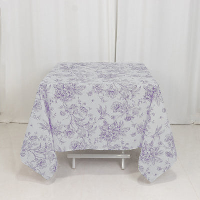 Purple floral tablecloth on a white table in a studio setting.