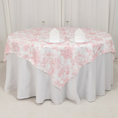 Round floral tablecloth with white base and pink design on a table.
