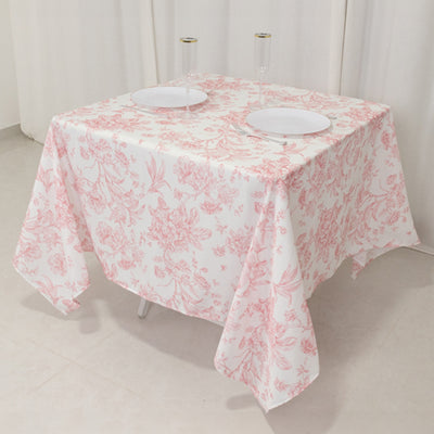 Floral patterned tablecloth draped over a table with plates and glasses set.