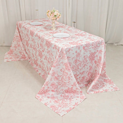 Floral patterned tablecloth draped over a table with plates and a vase.