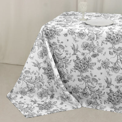 Floral patterned tablecloth on a table with a plate and glass.