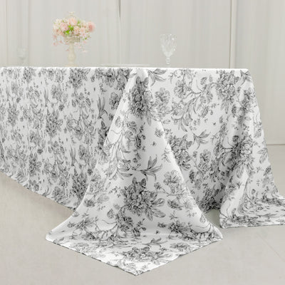 Floral tablecloth draped on a table with a decorative vase and glassware.