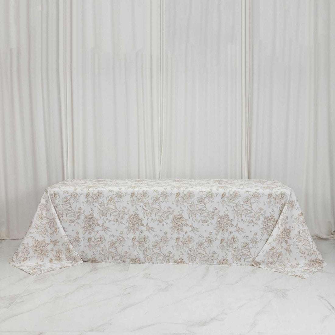 Elegant floral tablecloth on a long table with white draped backdrop