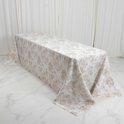 Elegant floral tablecloth draped over a long rectangular table in a white room