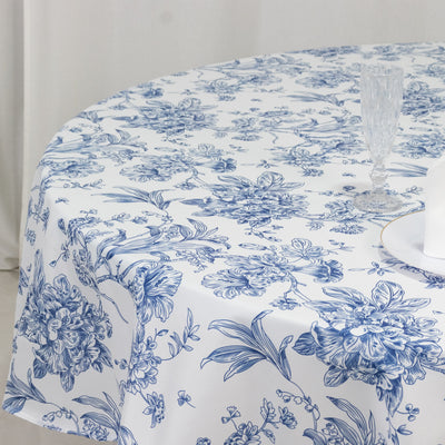Blue floral tablecloth on a round table with glassware and a plate.