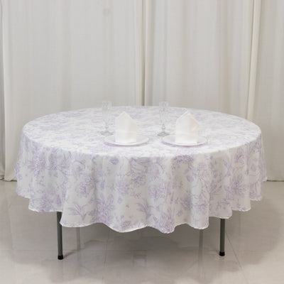 Round table set with floral tablecloth, plates, and glasses.