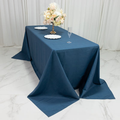 Elegant blue tablecloth set for a dining table with floral centerpiece.