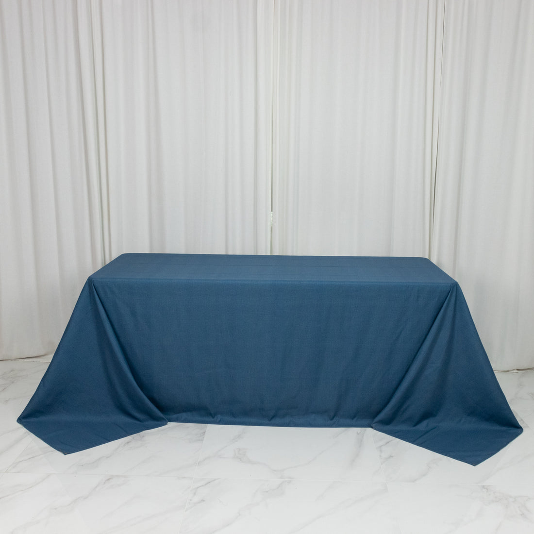 Blue tablecloth draped over a table against a plain backdrop.