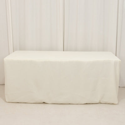 White table cover draped over a rectangular table in a studio setting.
