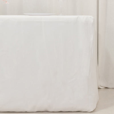 White tablecloth draped over a table with a plate and glass on top.