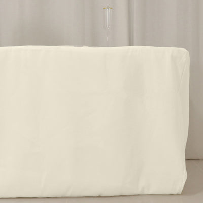 White table cover draped over a table with a glass on top.