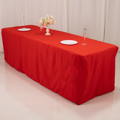Red tablecloth draped over a long table with floral centerpiece and dinnerware.