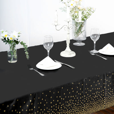 Elegant black tablecloth with gold polka dots, set for a dinner party.