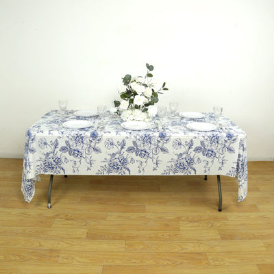 Floral tablecloth set on a dining table with plates and decorative flowers.
