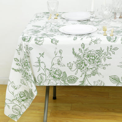 Floral patterned tablecloth draped over a table with plates and glassware.