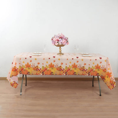 Autumn-themed tablecloth with pumpkins and leaves on a dining table.