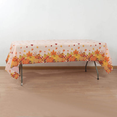 Fall-themed tablecloth with pumpkins and leaves on a wooden table.
