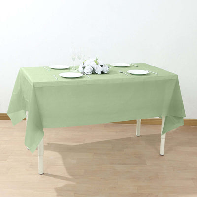 Green tablecloth on a dining table set with plates and a floral centerpiece.