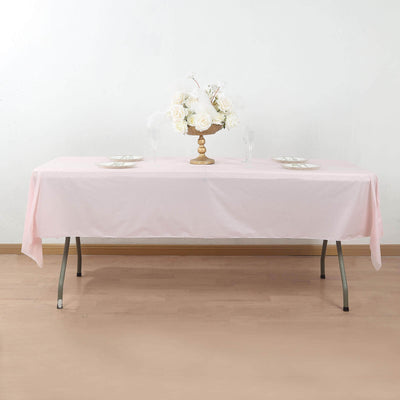 Pink tablecloth draped over a table with floral centerpiece and dinnerware.