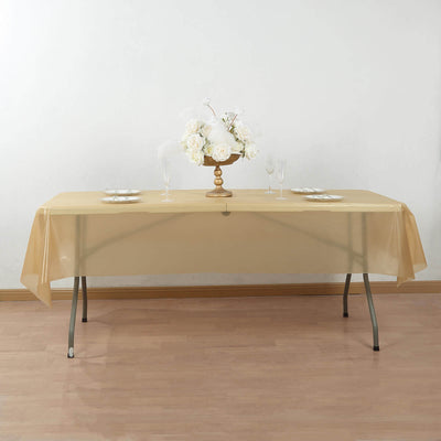 Gold tablecloth on a dining table with floral centerpiece and glassware.