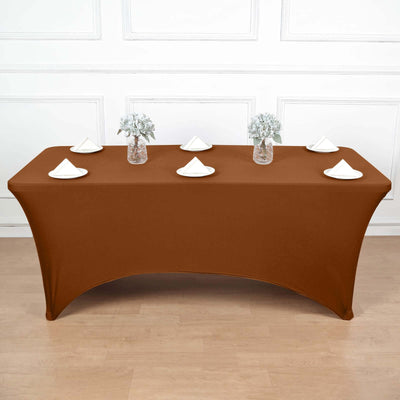Brown fitted table cover with decorative napkins and vases.