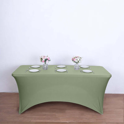 Green fitted table cover with plates and floral centerpieces.